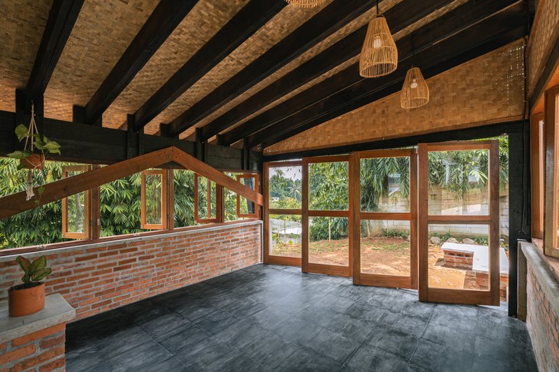 Interior space with woven bamboo ceiling panels and timber-framed glass doors facing garden