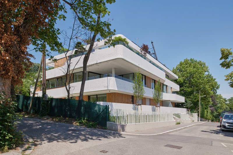 Street corner view of the building surrounded by mature trees in summer foliage