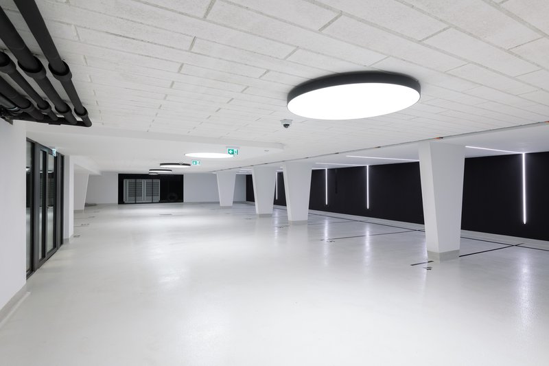 Underground parking garage with white epoxy floor, angled columns, and black recessed lighting panels