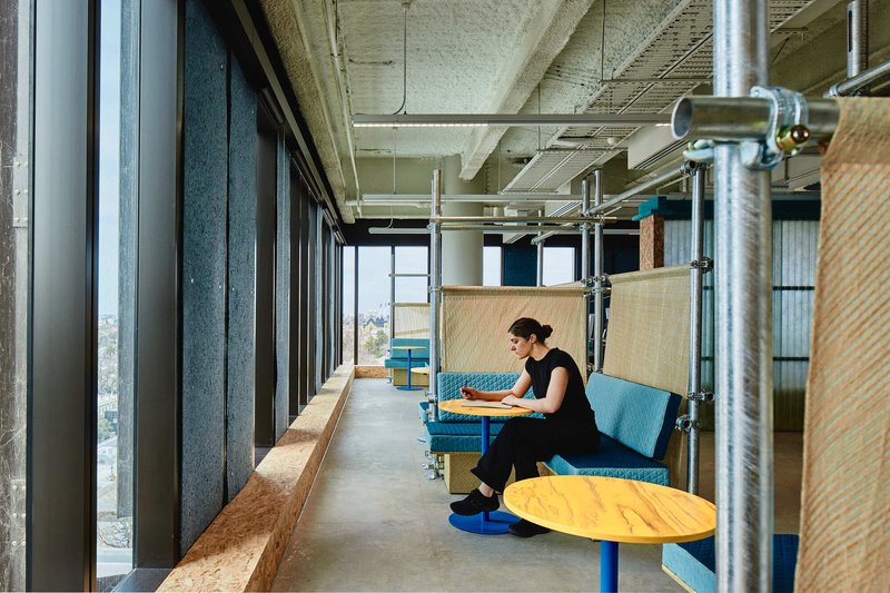 Window counter with built-in seating and a person working at low table with yellow top
