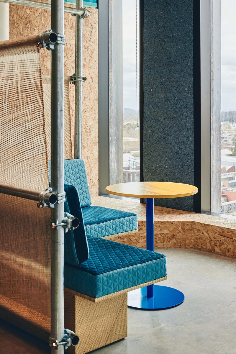 Window seating nook with upholstered benches and round table overlooking the urban roofscape