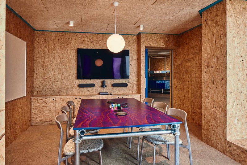 Meeting room with oriented strand board walls and cork ceiling around a marbled resin table