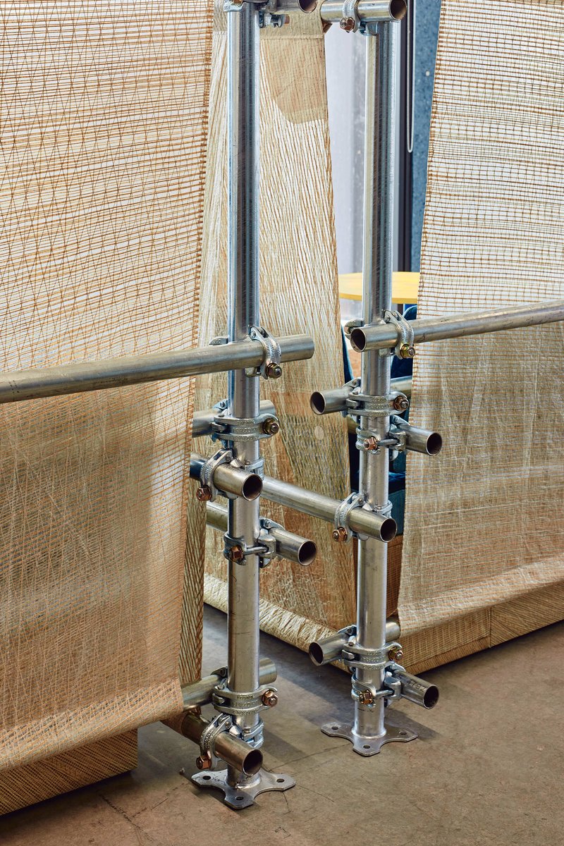 Scaffolding assembly with chrome pipe joints and fittings against translucent mesh partitions