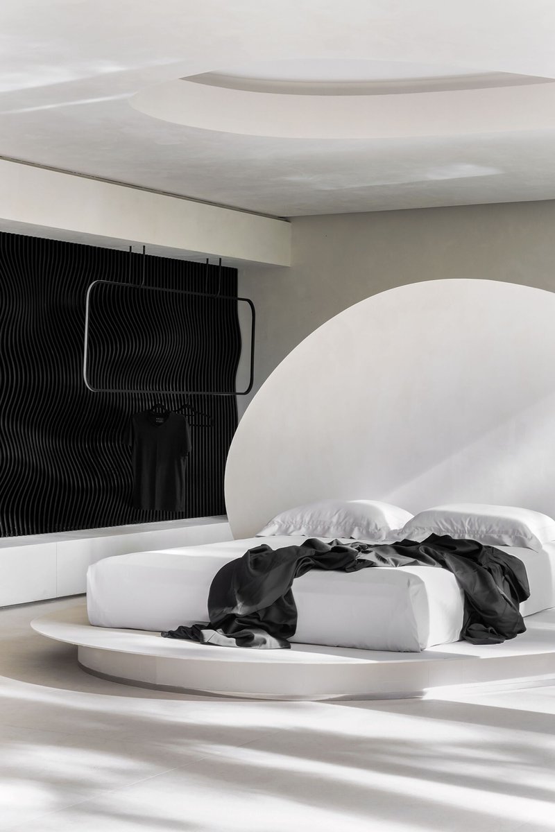 Oblique view of the rounded headboard niche and ribbed black accent wall in soft daylight