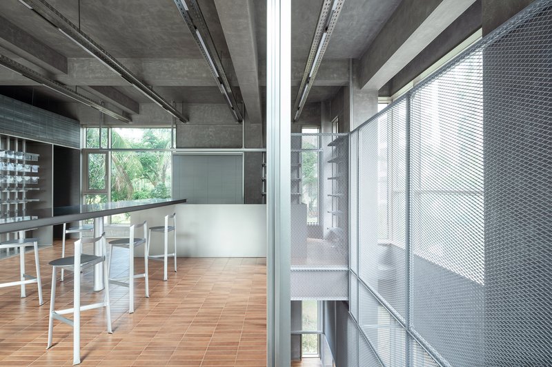 Upper-level workspace with perforated metal stair enclosure and exposed concrete ceiling structure