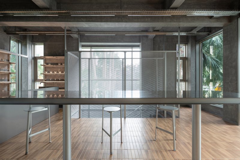 Open workspace with timber flooring and perforated metal screens dividing the exposed concrete interior