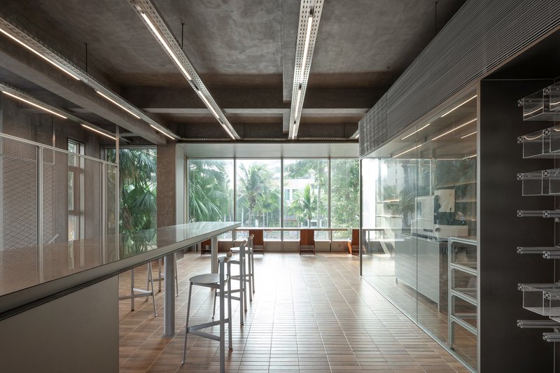 Open work area with full-height glazing overlooking palm trees and perforated metal mesh partitions