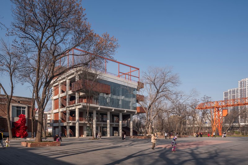 View across a plaza showing the piloti ground level and bare winter trees with children playing nearby
