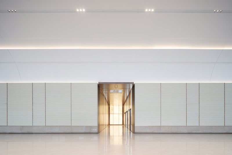 Interior corridor wall with horizontal ribbed panels and illuminated central passage through the recessed lighting