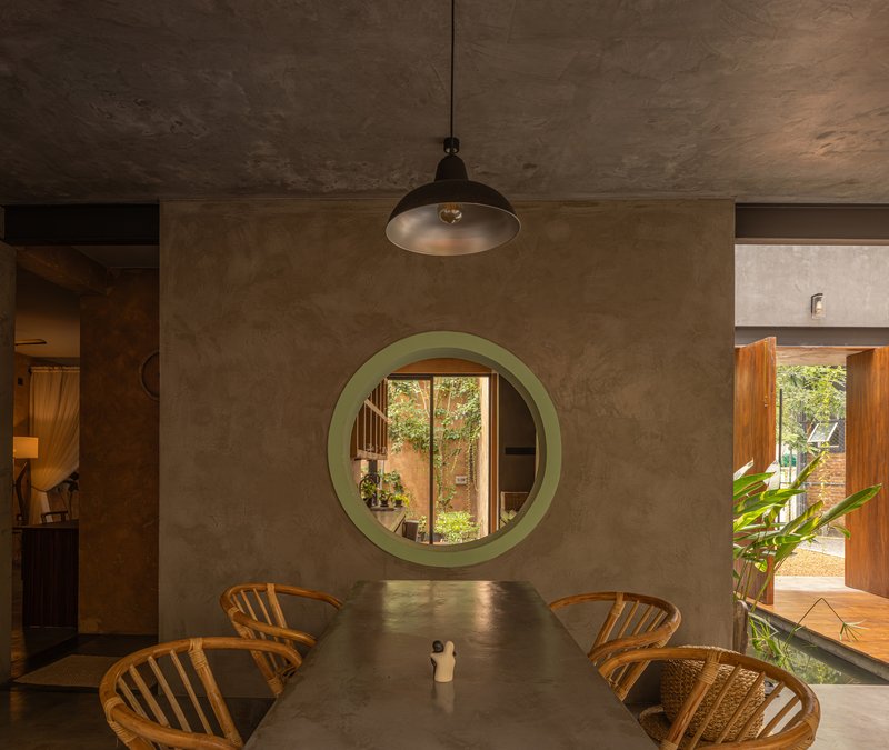 Dining area with circular green portal opening to a planted courtyard beyond