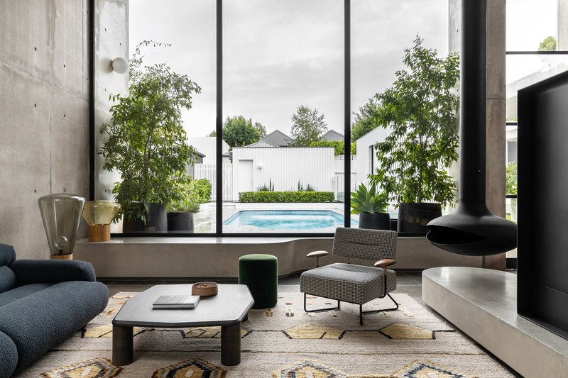 Living room with full-height glazing framing view of outdoor pool and potted trees