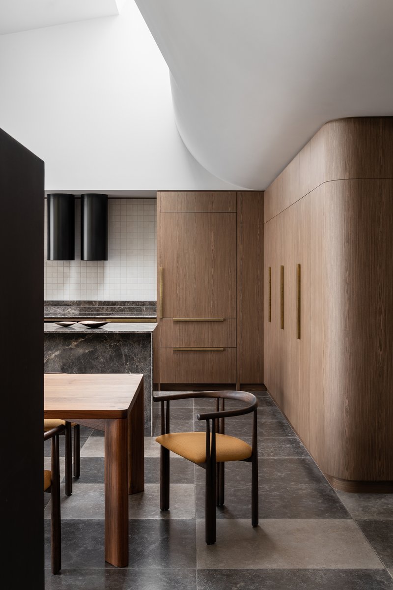 Kitchen with curved timber cabinetry beneath a smooth white vaulted ceiling
