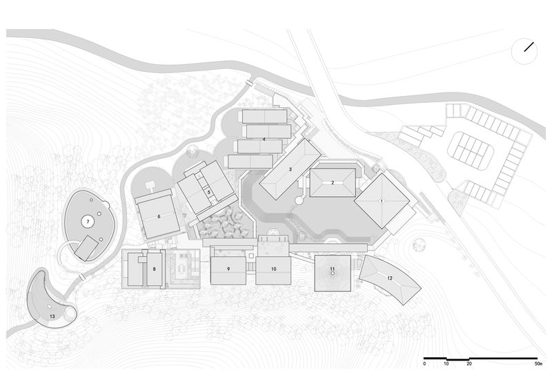 Site plan drawing showing multiple rectangular volumes arranged across sloping terrain with topographic contours and pathways