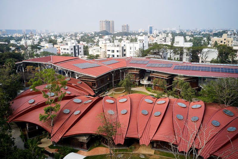 The ribbed metal roof with circular skylights extending over a central courtyard with trees and pathways