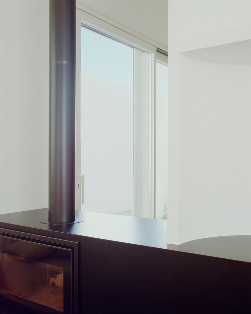 Black wood-burning stove beside sliding glass door overlooking a muted sky