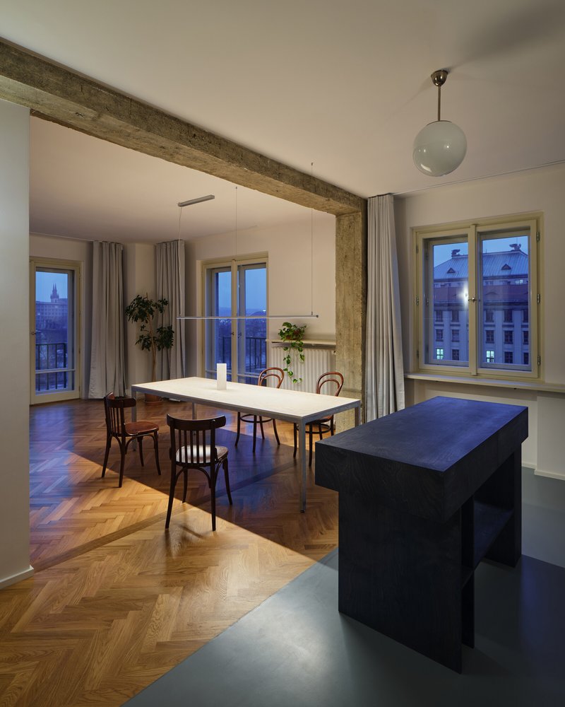 Dining area at dusk with herringbone oak floor, blue kitchen bench and windows overlooking the city