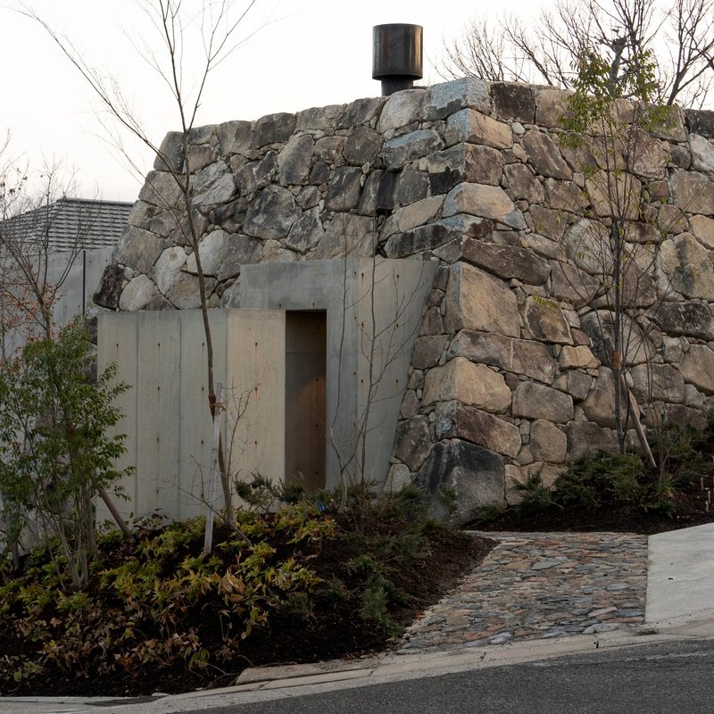 Concrete entrance portal set into a boulder face with a black chimney cap above