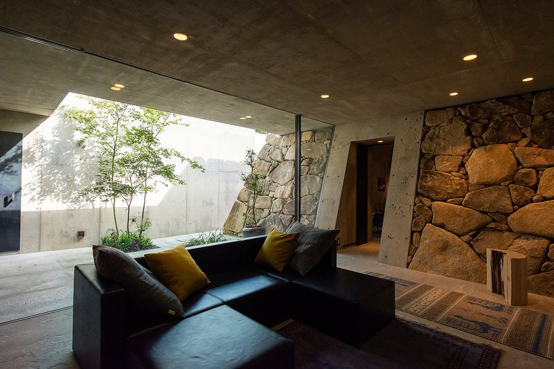 Living area with dark sofa looking toward the glazed courtyard opening in afternoon light