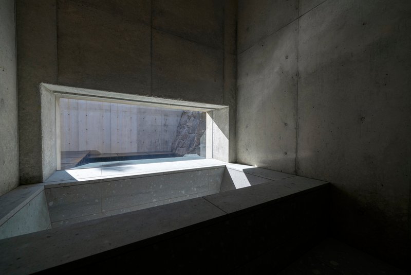 Horizontal window carved into board-formed concrete walls with bright daylight streaming through