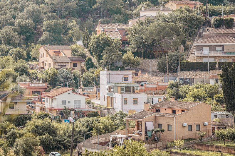 Hillside residential cluster with a timber-framed dwelling among traditional stone and stucco houses