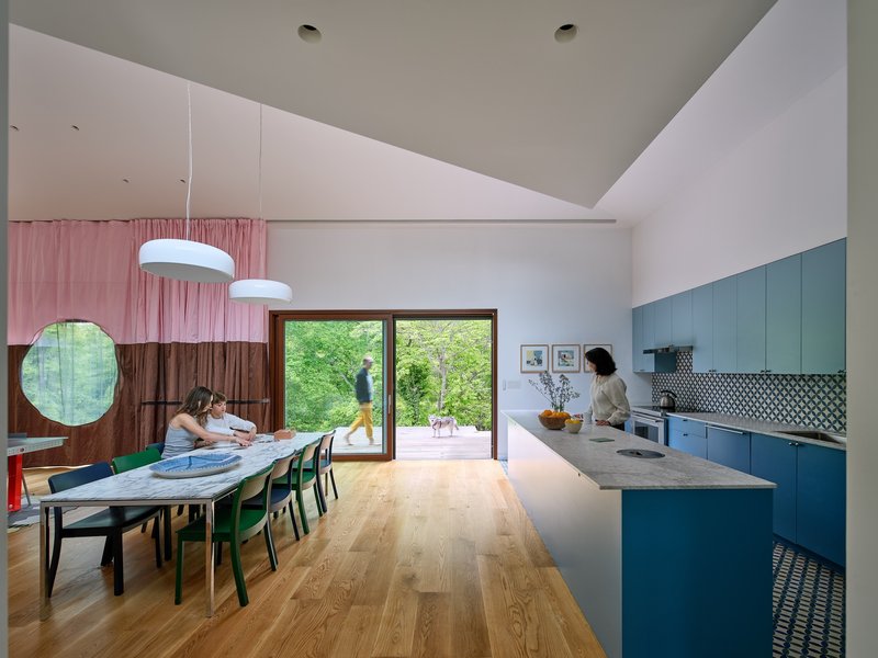 Open-plan kitchen and dining room with blue cabinetry, vaulted ceiling, and glazed doors to garden