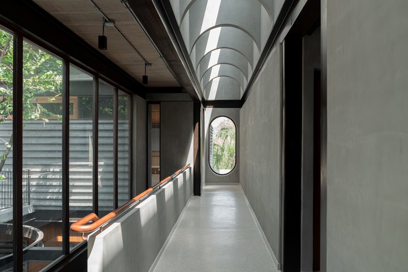 Concrete corridor with arched ceiling and oval window at the far end