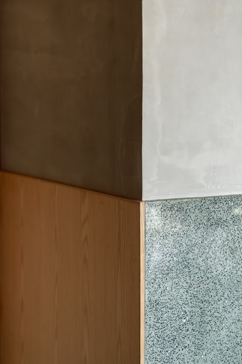Corner detail where timber cabinetry meets polished concrete ceiling and terrazzo wall panel