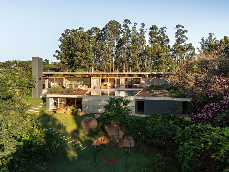 Two-story residence with timber roof cantilevering over glass walls and a terrace edged by tall eucalyptus trees