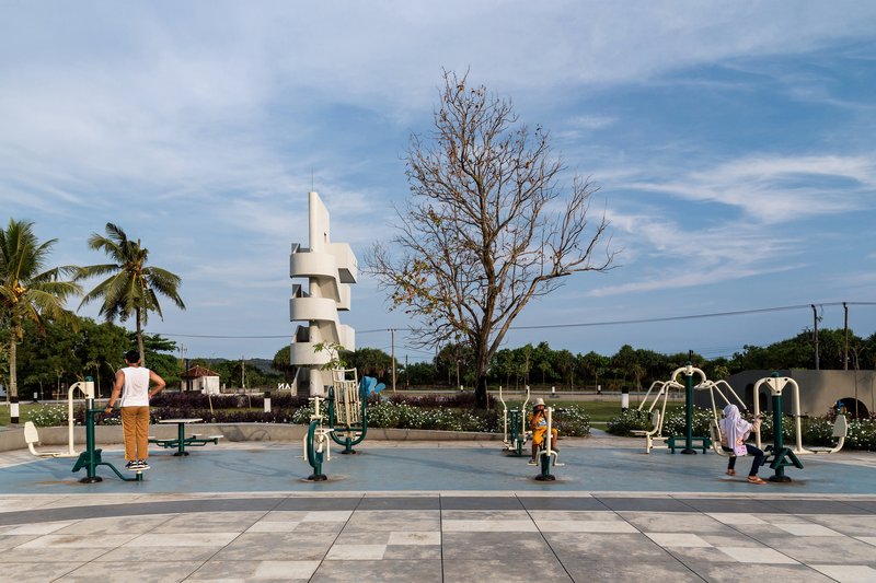 Outdoor exercise equipment area with spiraling white tower and visitors beneath a bare tree