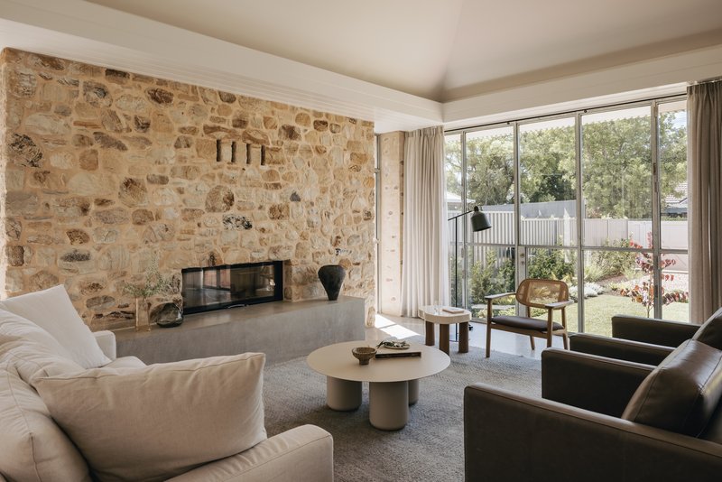 Living room with stone fireplace wall and floor-to-ceiling glass doors overlooking the garden