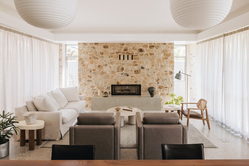 Living room with sandstone fireplace wall flanked by sheer curtains and two paper lanterns overhead
