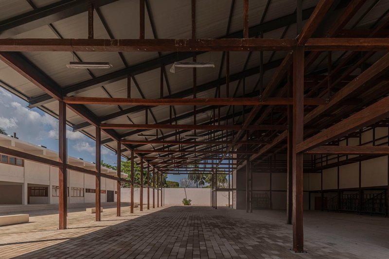 Covered corridor with timber post-and-beam structure framing views to a planted courtyard beyond