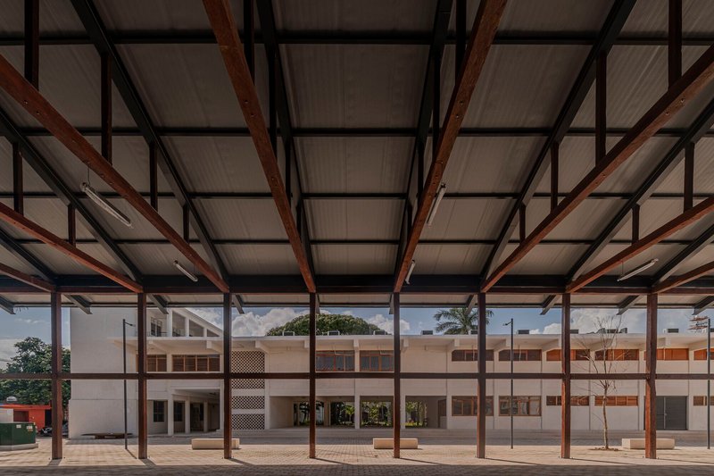Covered open-air hall with exposed timber beams and steel columns framing the courtyard beyond