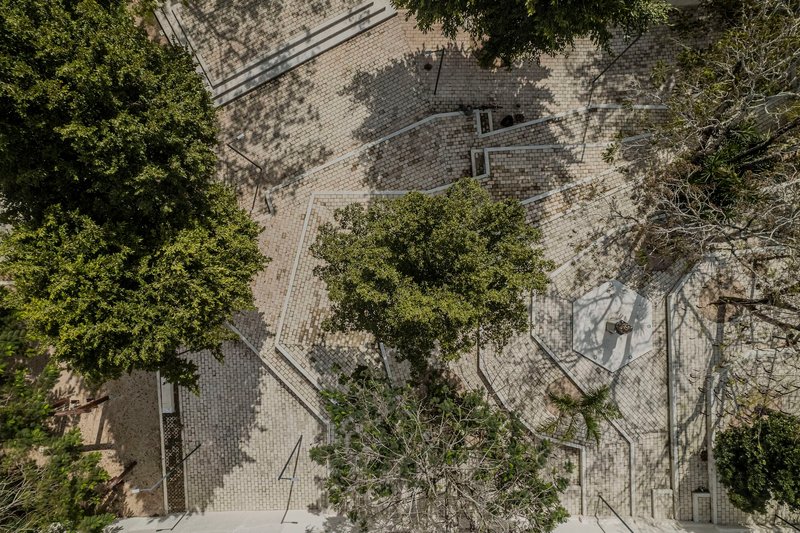 Aerial perspective of courtyard with varied paving textures, preserved mature trees, and geometric walkways