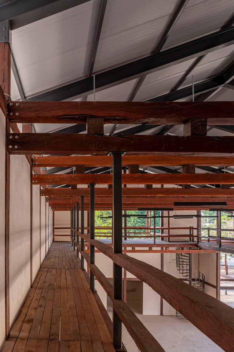 Upper walkway with timber decking and horizontal railings framing views to the landscape beyond