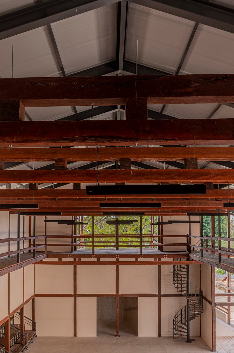 Interior view showing exposed timber beams and joists beneath a translucent ceiling with two spiral staircases below