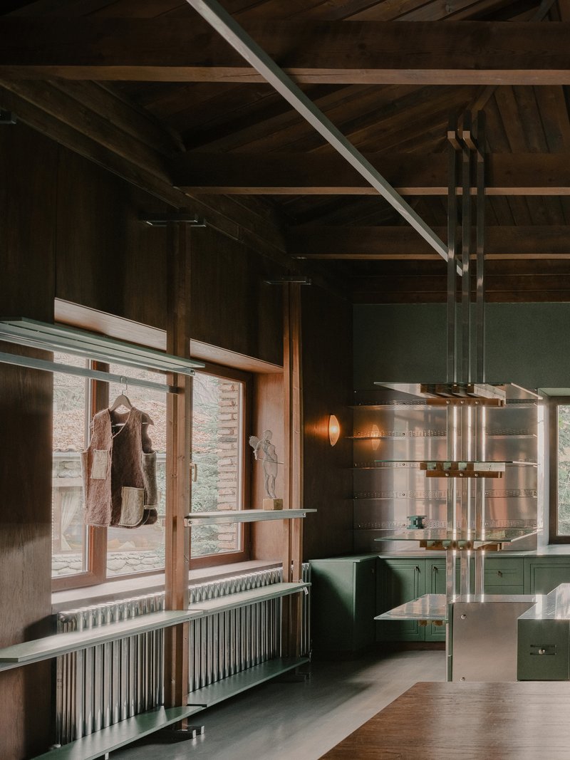 Interior view of shelving system beside timber-framed windows with radiator and view to exterior courtyard
