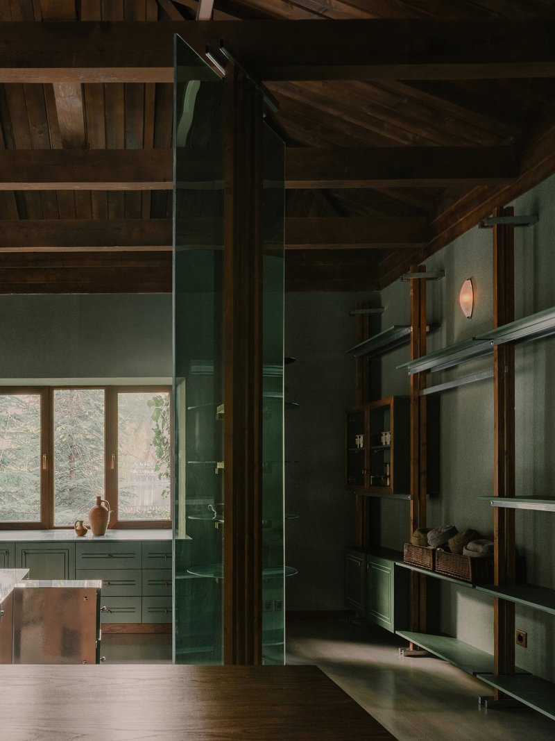 Tall green glazed partition wall beneath exposed timber rafters with natural light filtering through windows