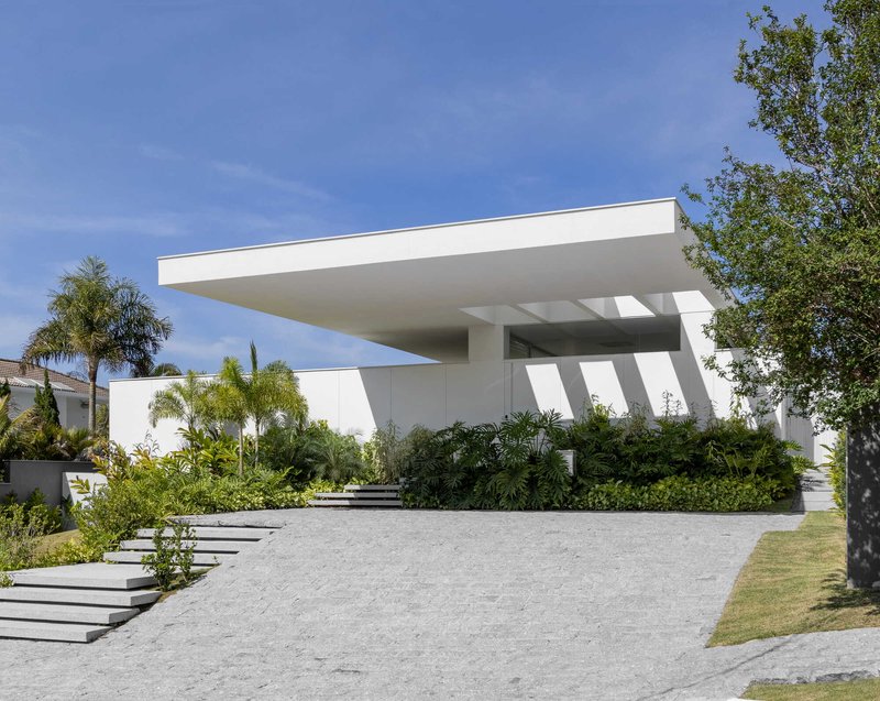 Entry facade with deep cantilevered roof plane and diagonal columns framed by palms