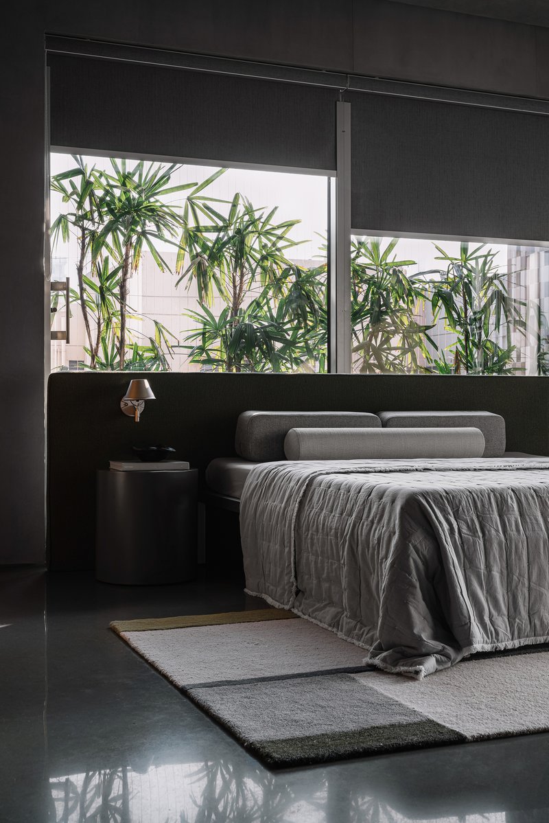 Bedroom with horizontal window framing bamboo plants in an adjacent courtyard