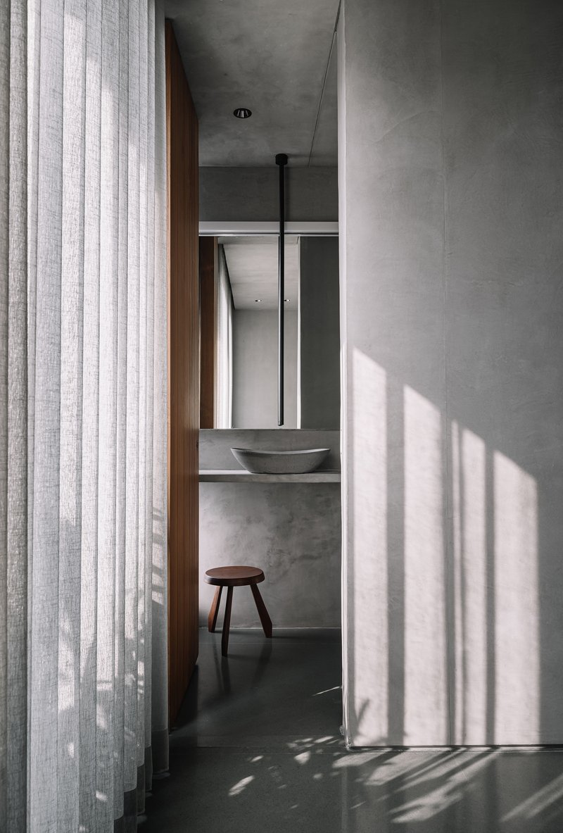 Powder room view through sheer curtains with slatted shadow patterns across dark floor