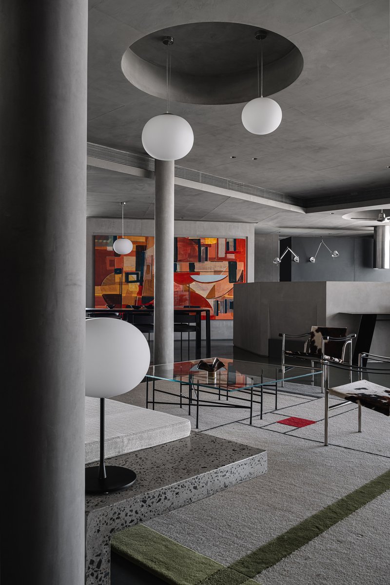 Open living space with round concrete columns, globe pendant lights, and terrazzo seating platform