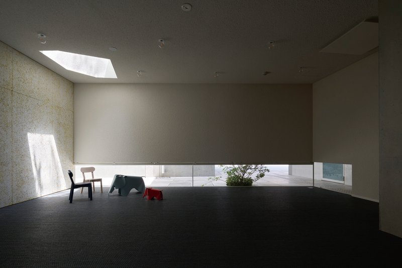 Dark carpeted room with skylight and horizontal window slot illuminating the textured wall surface
