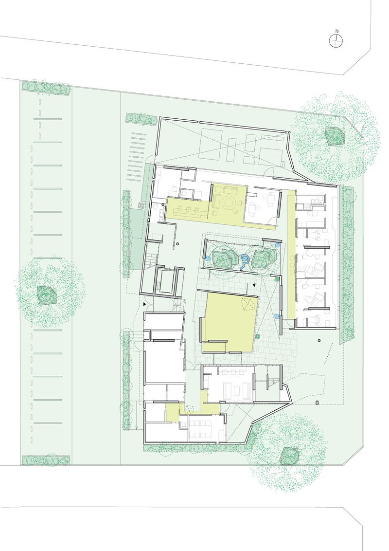 Site plan drawing depicting the building layout with courtyards and surrounding landscape including trees
