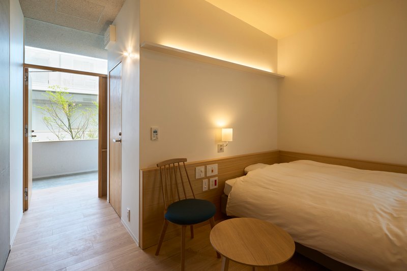 Bedroom with timber headboard and open door leading to a small terrace with tree