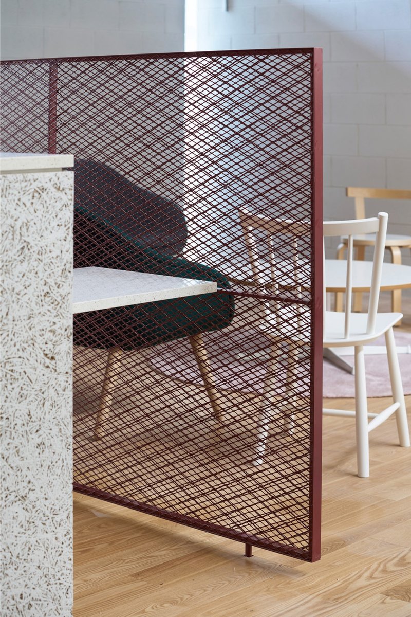 Copper mesh screen with maroon frame dividing a room with terrazzo block and timber flooring