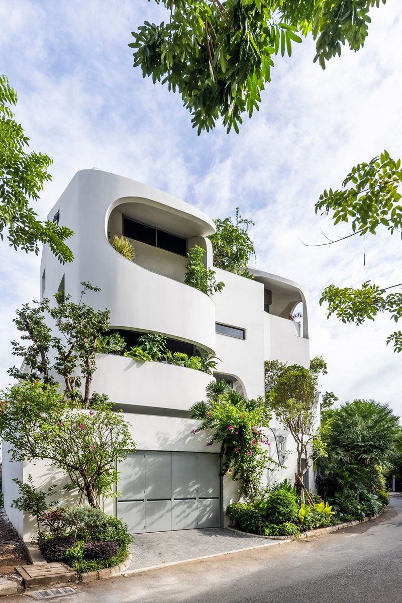 Street view of the white stacked volumes with integrated planters and climbing greenery