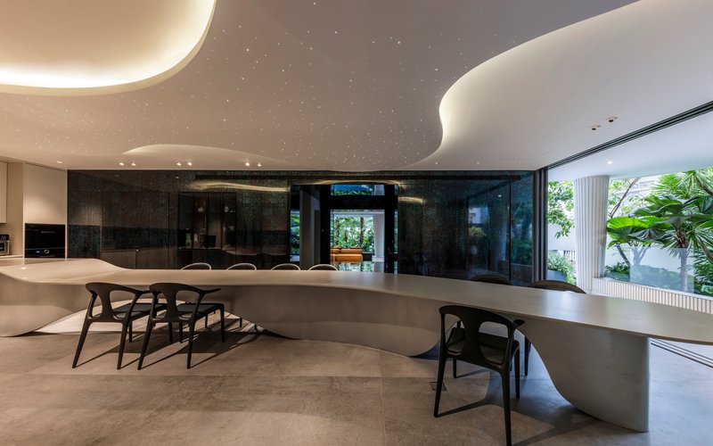 Dining area with curved white counter and backlit ceiling clouds beneath black cabinetry