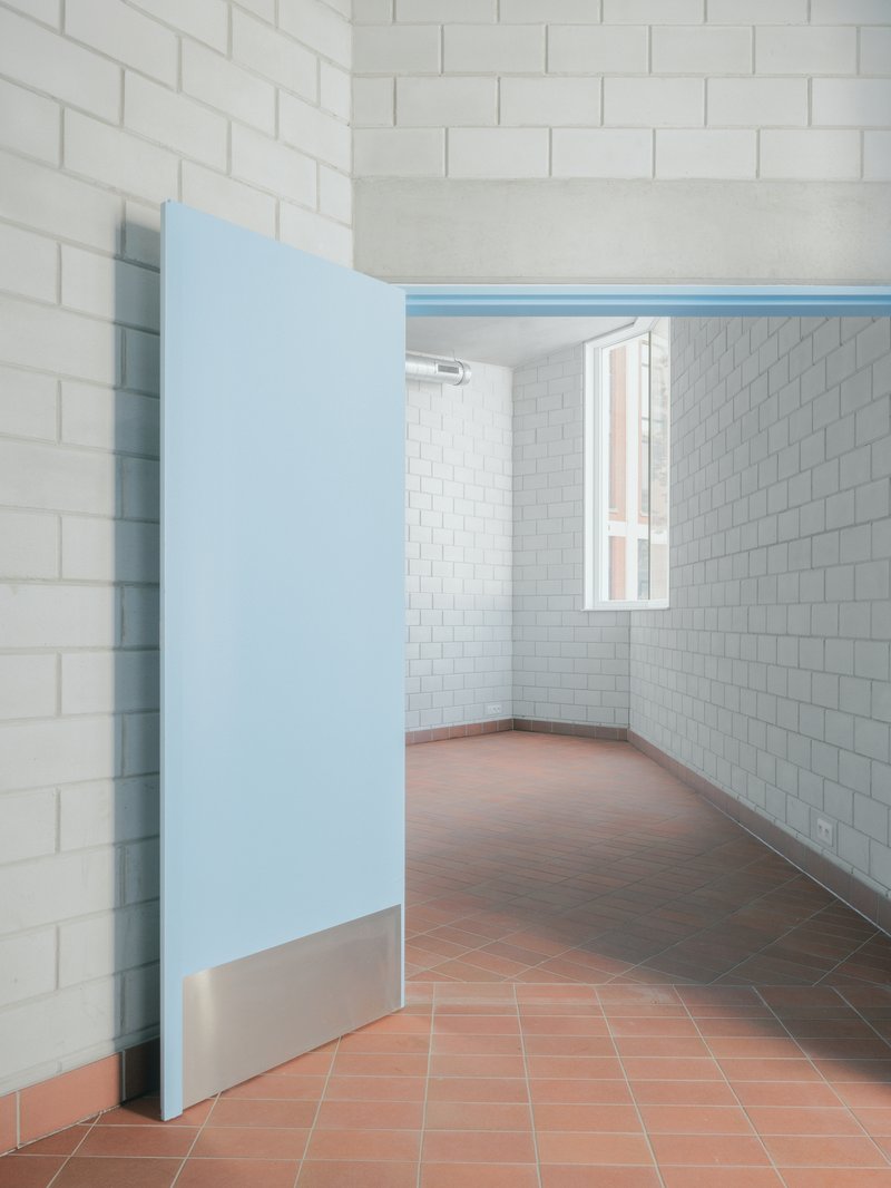 Interior room with white subway tile walls, terracotta floor and partially open pale blue door
