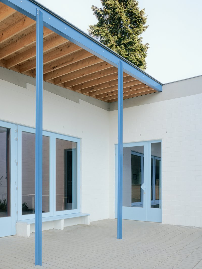 Covered patio with pale blue steel columns supporting exposed timber joists and rafters overhead